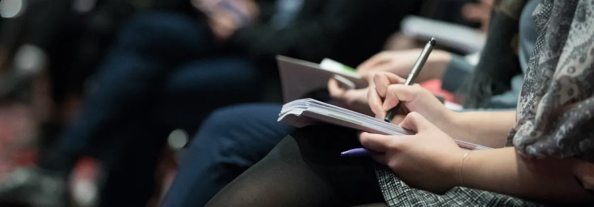 A conference attendee takes notes