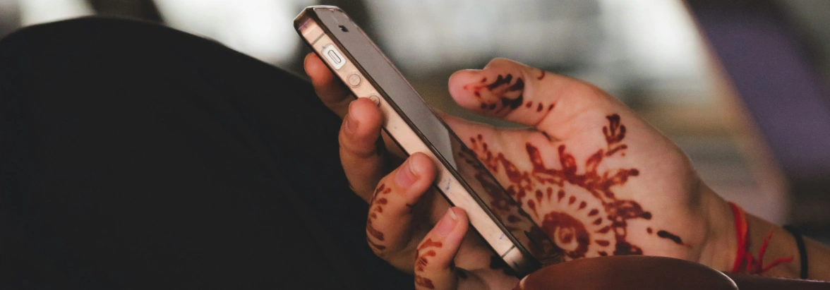 A Hand with Henna Tattoos holds a Smartphone
