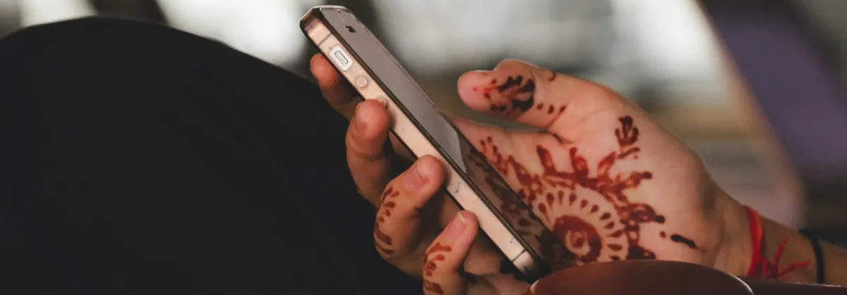 A Hand with Henna Tattoos holds a Smartphone