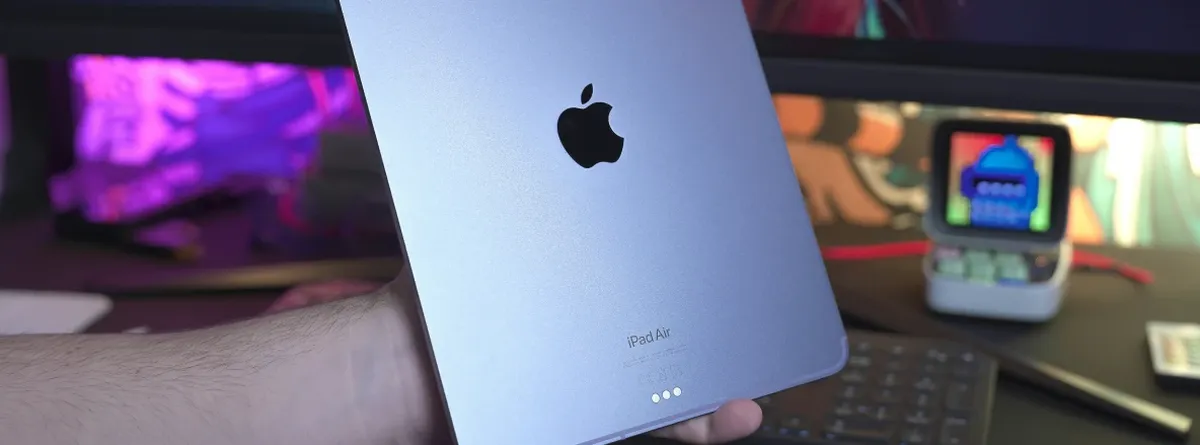 A hand holds up an iPad Air, seen from the back