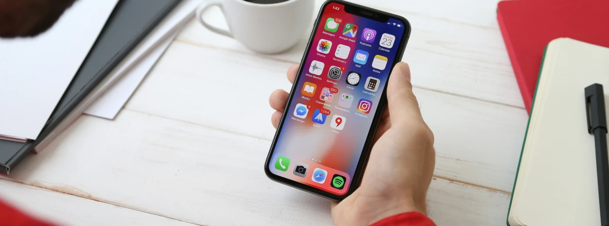 Successful Mobile Services - A man holding a mobile phone while seated at a white desk