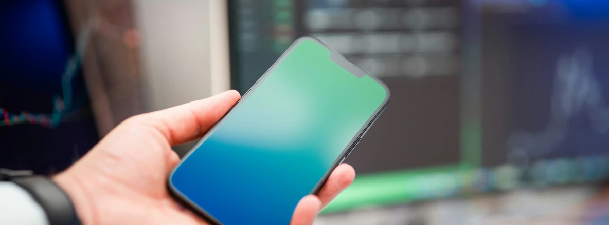 Connectivity Data - a hand holding a mobile phone in front of computer screens