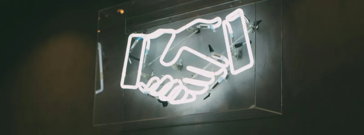 A white neon sign representing a handshake