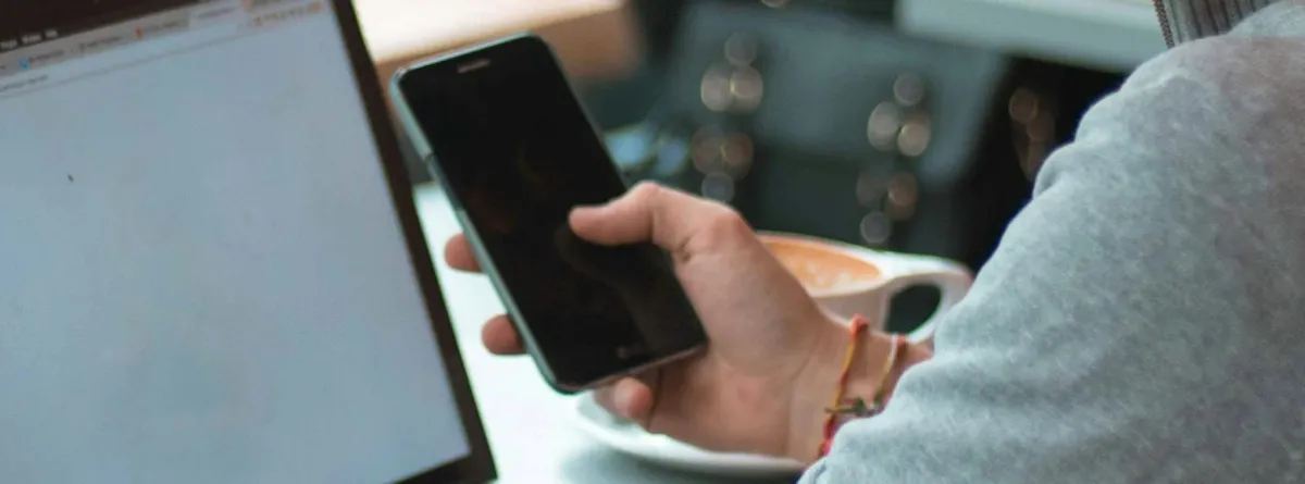 A person looks at their smartphone while working in a cafe