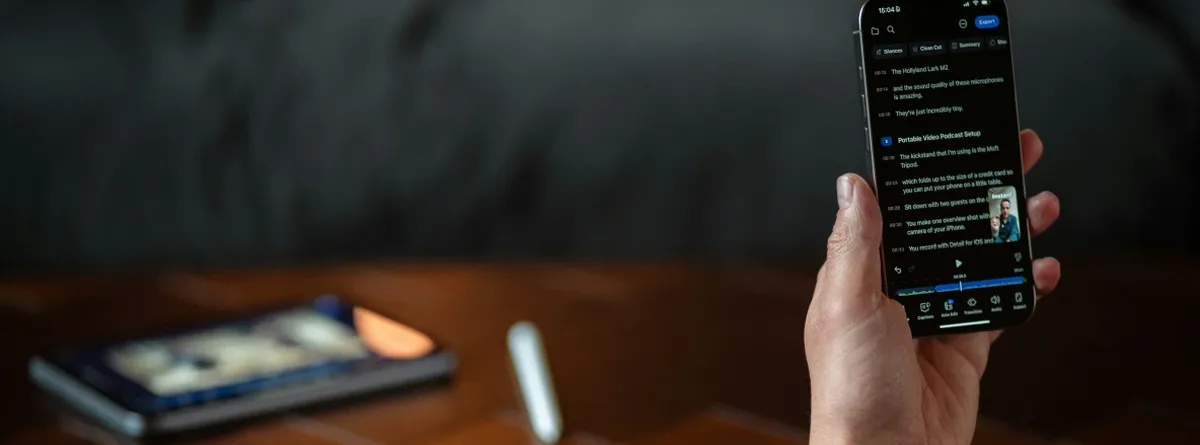Compliance Resilience - hand holding a mobile phone with a tablet on the desk behind