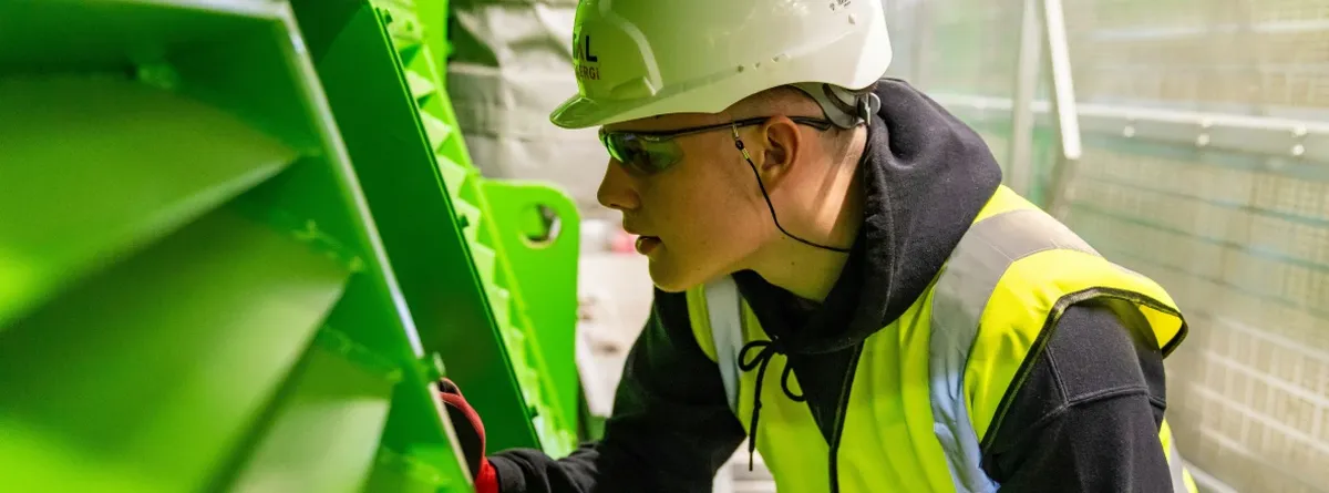 Smarter, not Harder - an employee in safety gear checking a green machine