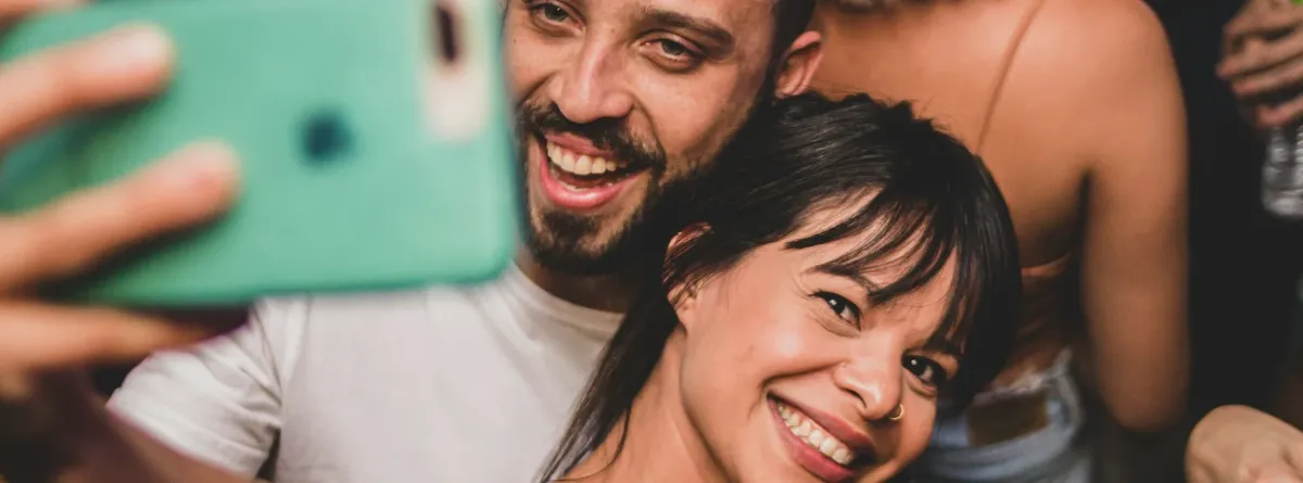 Unlocking the next connectivity wave - two partygoers take a selfie with a green mobile phone