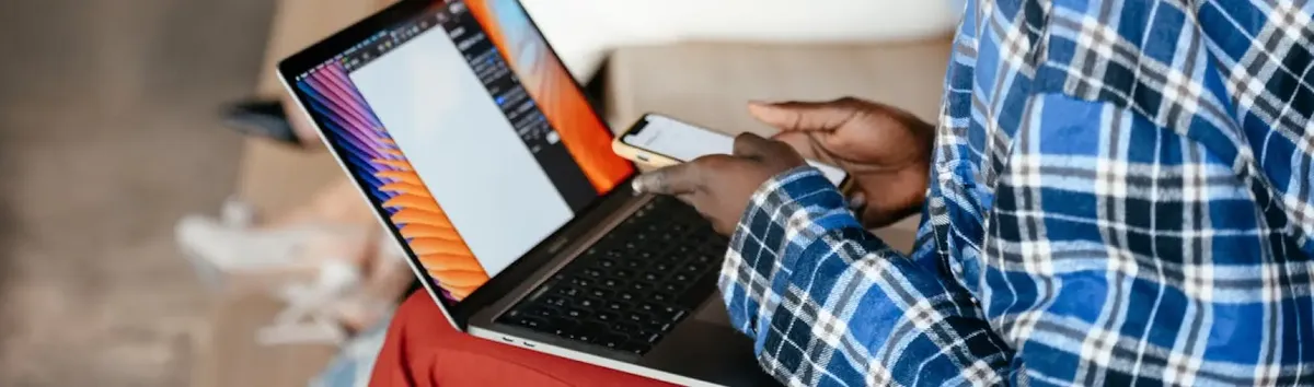 A person using an iPhone and laptop simultaneously