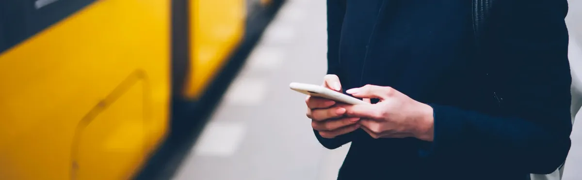 A person checking their smartphone next to a tram