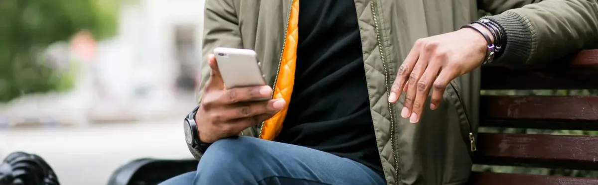 eSIM challenges - A person on a park bench using an eSIM on their smartphone