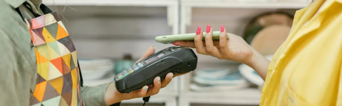 Two people conducting an in-store transaction with a contactless card reader and a smartphone