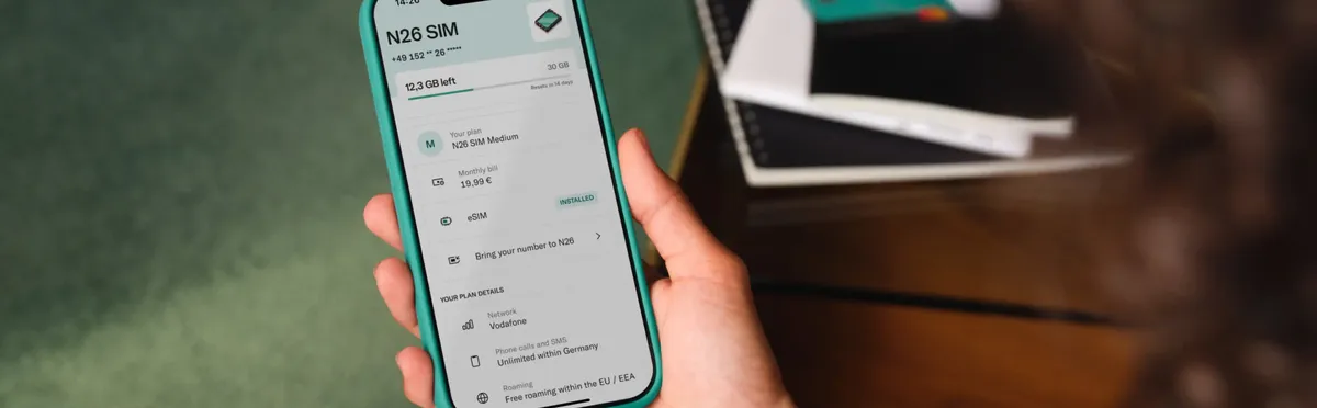 A hand holding a phone, using the N26 app to book an eSIM mobile plan