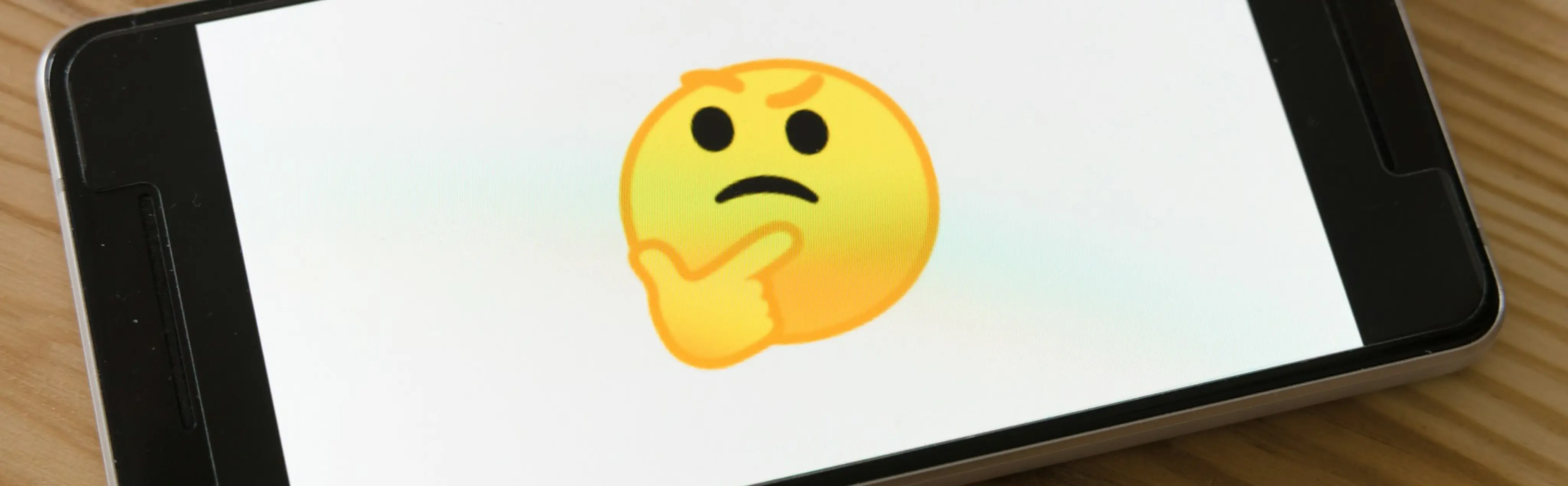A "thinking face" emoji on a smartphone screen