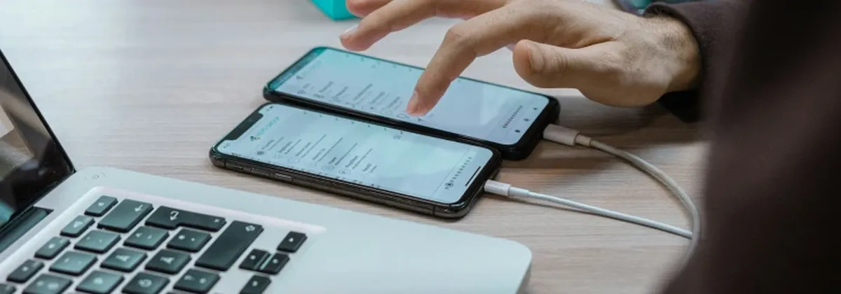 Carrier Fragmentation - woman's hand operating two mobile phones next to a laptop
