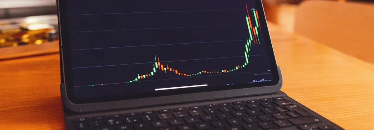Introduction to MiFID III - black laptop displaying rising investments, set against a brown desk